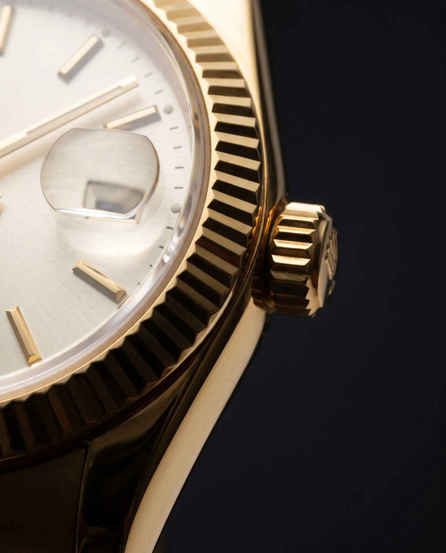 Macro of a fluted gold bezel and winding crown