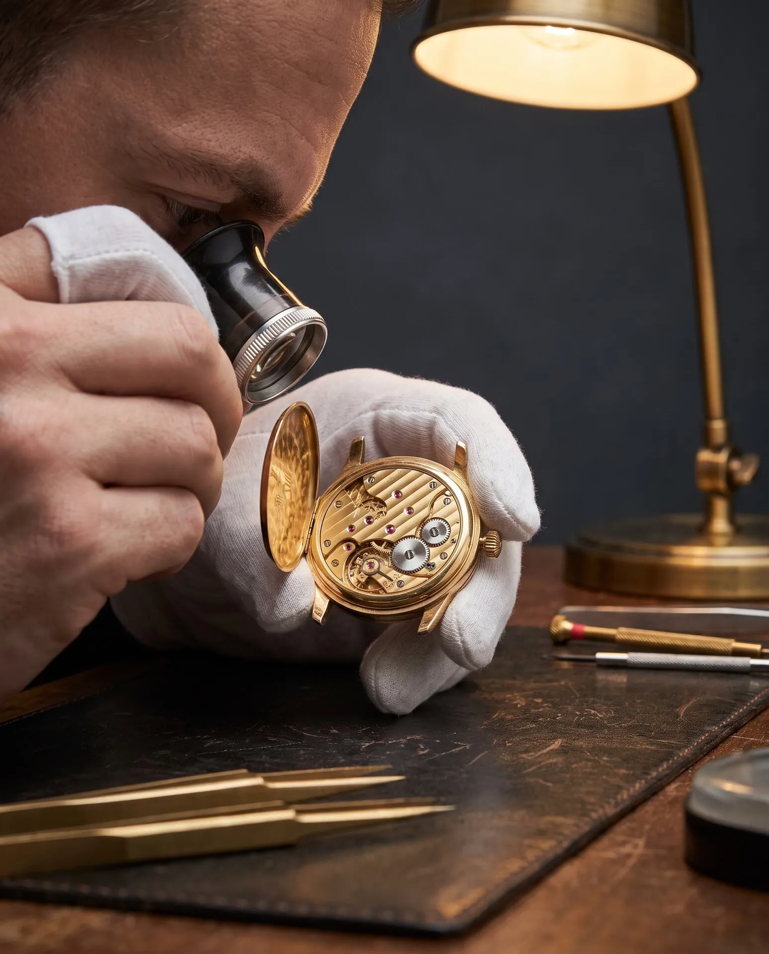 Crown Auctions specialist inspecting a gold watch movement through a loupe